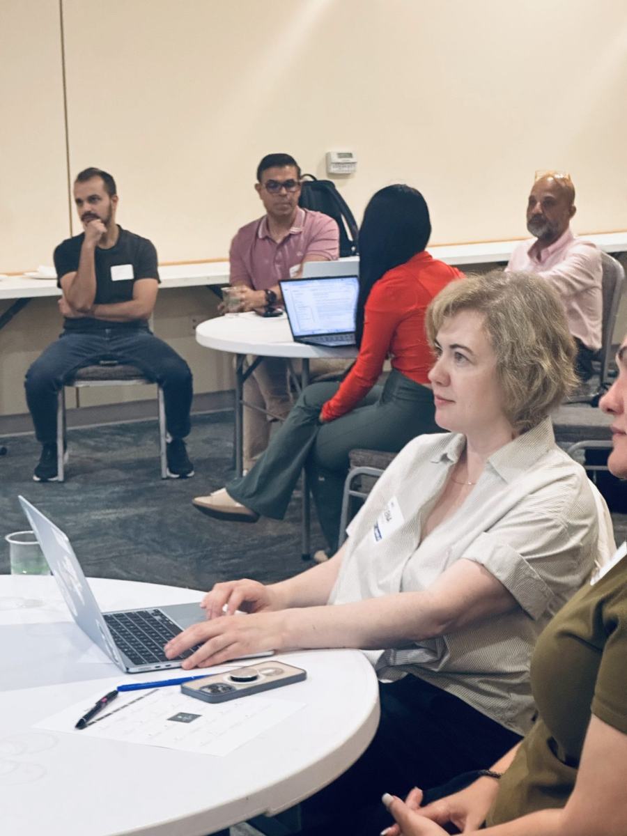 Attendees at round tables with laptops open, following along during the hands-on portion.